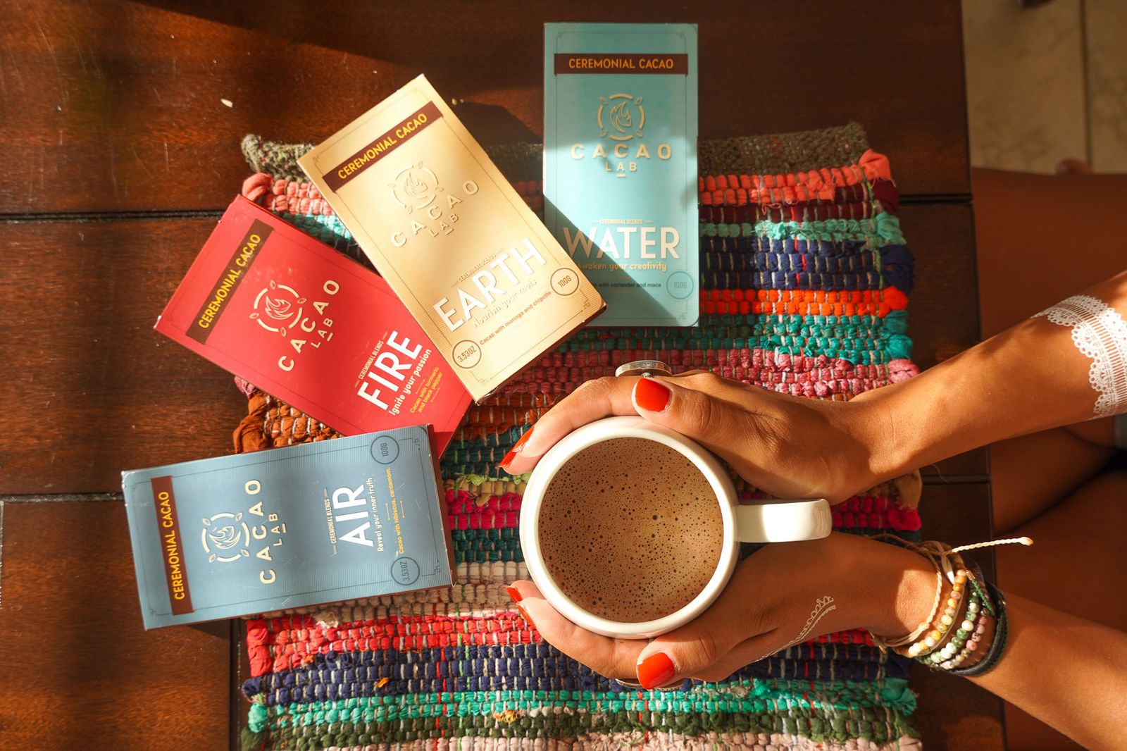 Hands holding a mug of cacao over a striped blanket