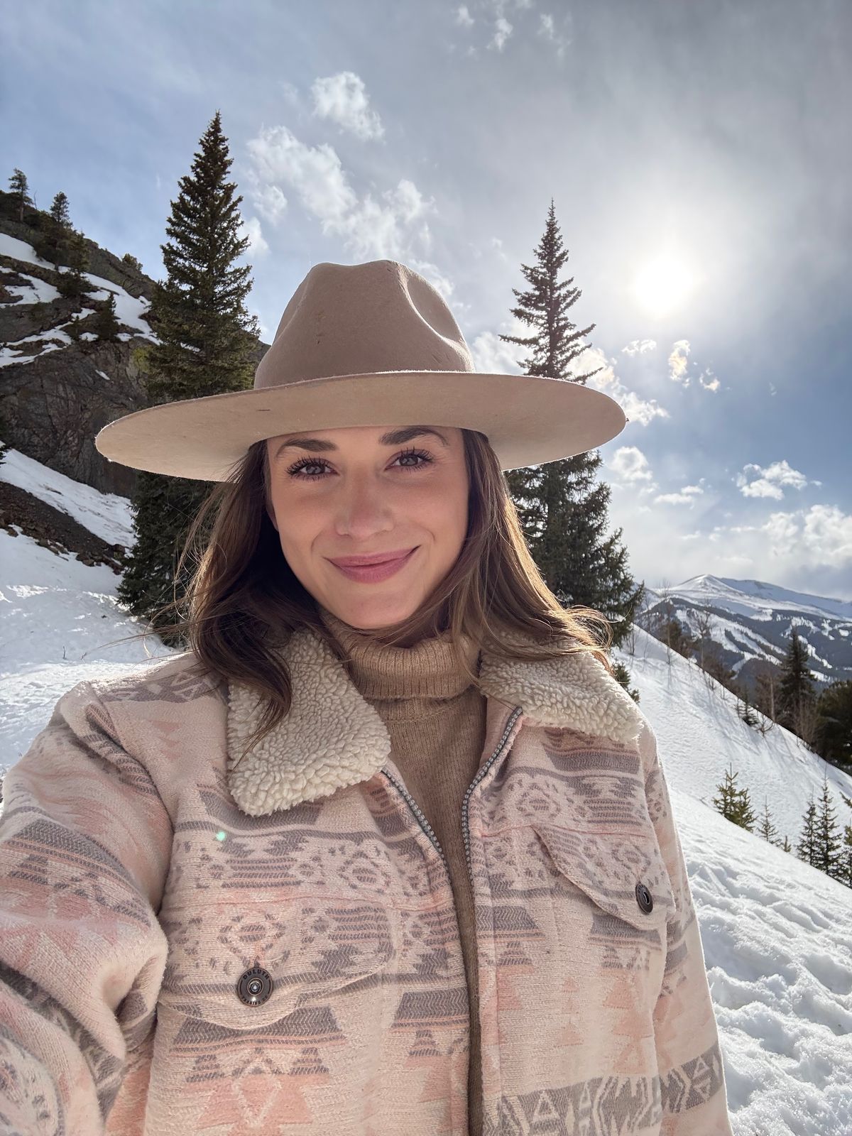 Chelsea in a wide-brim hat on a snowy mountainside